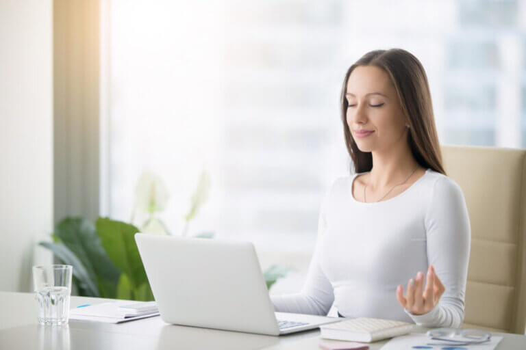 A woman at a desk with a laptop, focused on her work related to wellness-infused beauty and emotional wellbeing marketing.